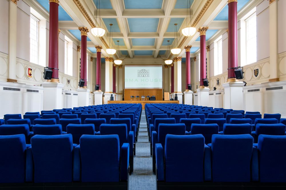 Photo of BMA House Great Hall Theatre with blue-colored seating facing a screen 