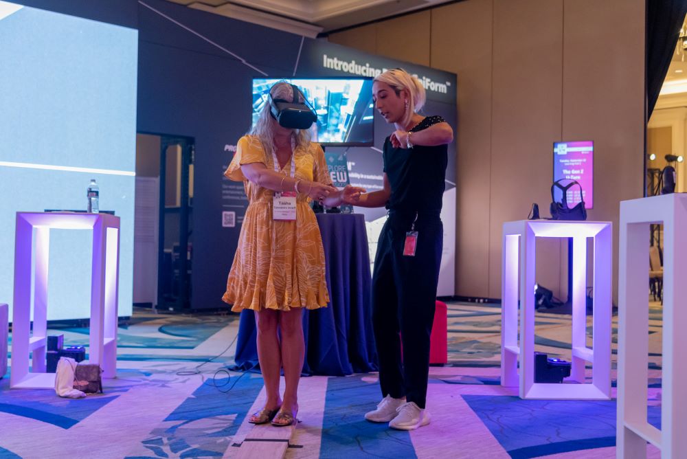 Photo of two women at Maritz Elevate event, with one wearing virtual reality goggles.