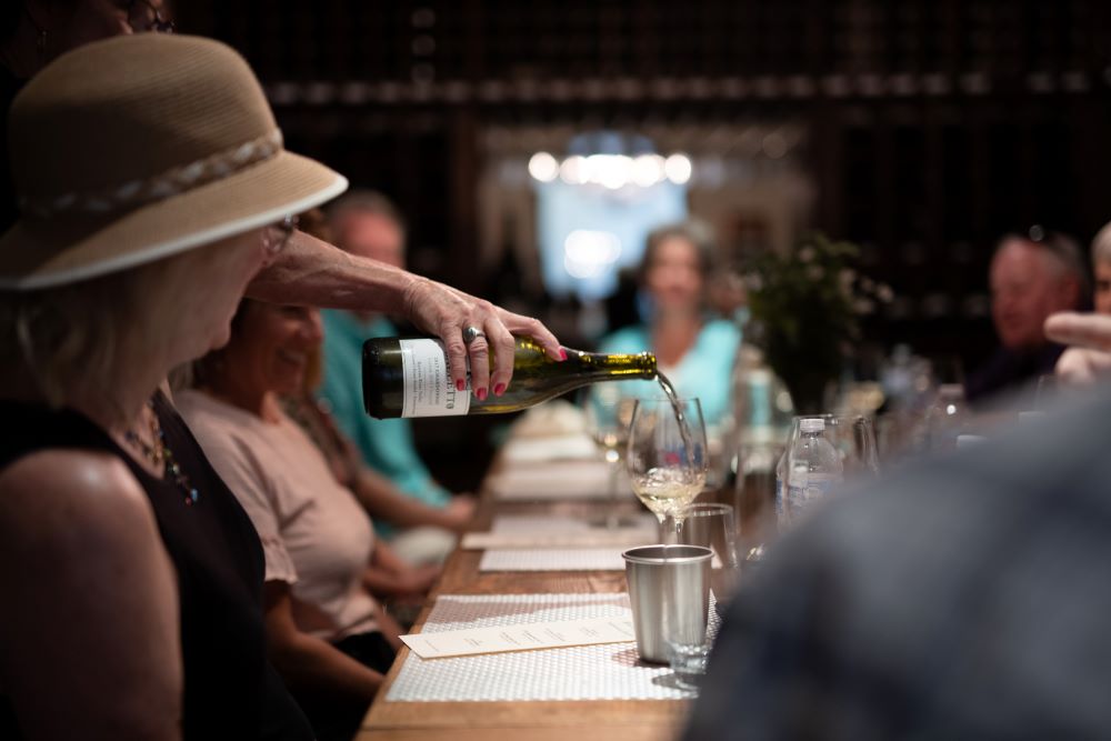 Photo of people tasting wine on a long table at Balletto Vineyards.