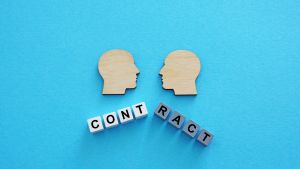 Image of two wood-block faces above the word contract.