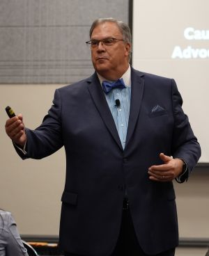 Photo of Roger Rickard speaking with a bow tie.