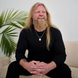 Photo of Justin Wren, sitting down in a black outfit.