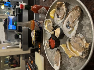 Photo of a plate of oysters on ice, with hot sauce in the background.