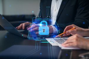 Image of two people, one signing a contract and another on a laptop, with an image of a padlock in the foreground.
