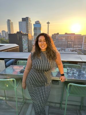 Photo of Reem Ismail standing in a checkered dress in Seattle.