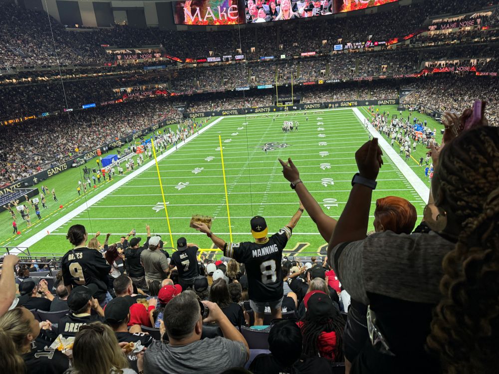 Photo of people cheering during a New Orleans Saints game at Caesars Superdome.