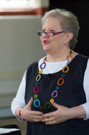 Photo of Joan Eisenstodt standing during teaching, wearing a colorful necklace.
