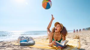 Photo of woman on beach with a beach ball over her foot.
