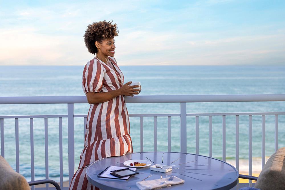 Business traveler working on a patio overlooking the ocean holding a cup of coffee in Ocean City, Maryland