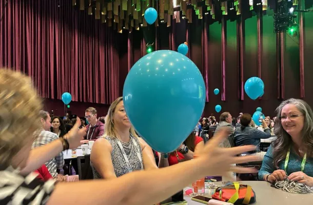 Photo of attendees at CEMA Summit 2024 interacting with balloons during a session.