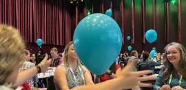 Photo of attendees at CEMA Summit 2024 interacting with balloons during a session.