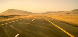 Photo of a road with sand blowing across it.