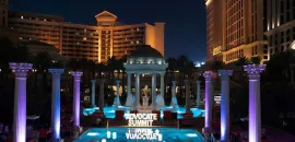 Photo of Caesars Palace pool with Advocate Summit sign lit up, at night.