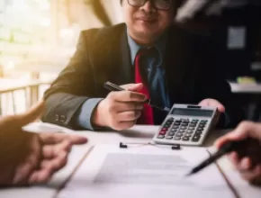 Person with a calculator examining a contract.