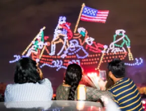 Family watches drone light show display on Fourth of July celebration