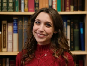 Photo of Taylor Smith standing in front of a wall of books.