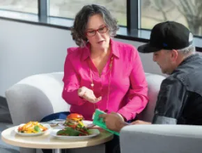 Photo of Tracy Stuckrath sitting on a couch, talking with chef.