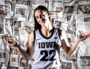 Caitlin Clark (22) shrugs in front of wall of newspaper articles about her during Hawkeyes women's basketball media day, Wednesday, Oct. 4, 2023, at Carver-Hawkeye Arena in Iowa City, Iowa.