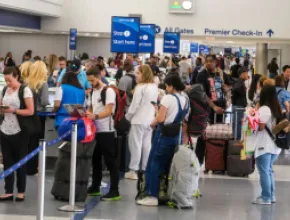 Photo of frustrated travelers standing in line at an airline check-in counter.