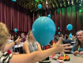 Photo of attendees at CEMA Summit 2024 interacting with balloons during a session.