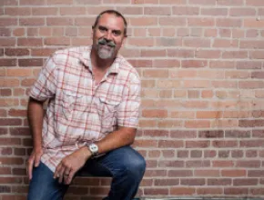 Photo of Mike McCallen standing in front of a brick wall.