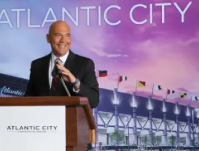 Photo of Larry Sieg, standing at a podium with a backdrop of the Atlantic City Convention Center in the background.