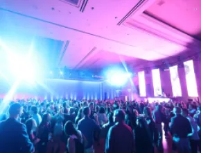 Photo of a crowd of attendees at a meeting, with spotlights in the room.