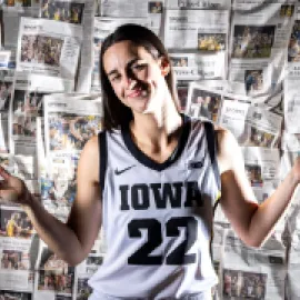Caitlin Clark (22) shrugs in front of wall of newspaper articles about her during Hawkeyes women's basketball media day, Wednesday, Oct. 4, 2023, at Carver-Hawkeye Arena in Iowa City, Iowa.