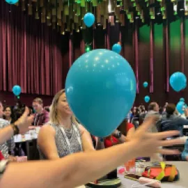 Photo of attendees at CEMA Summit 2024 interacting with balloons during a session.