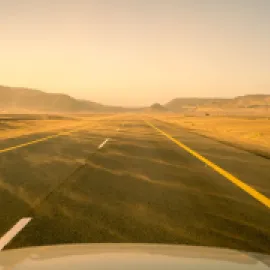 Photo of a road with sand blowing across it.