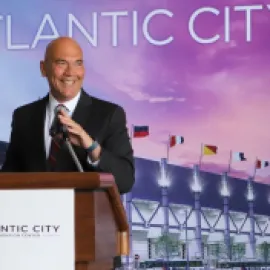 Photo of Larry Sieg, standing at a podium with a backdrop of the Atlantic City Convention Center in the background.