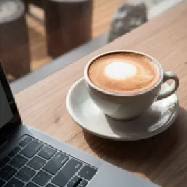 Cup of coffee on a table next to a laptop