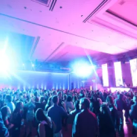 Photo of a crowd of attendees at a meeting, with spotlights in the room.