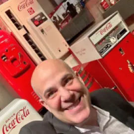 image of futurist Scott Steinberg standing in front of antique Coca-Cola vending machines.