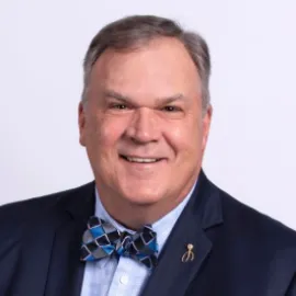 Roger Ricard in a dark blue suit with a checked bow tie.