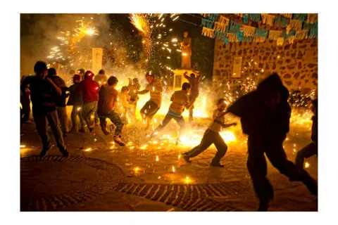 Revelers old and young dance around a makeshift torito, or bull, loaded with fireworks at Virgin of Guadalupe celebrations during December in Tequila, Jalisco.