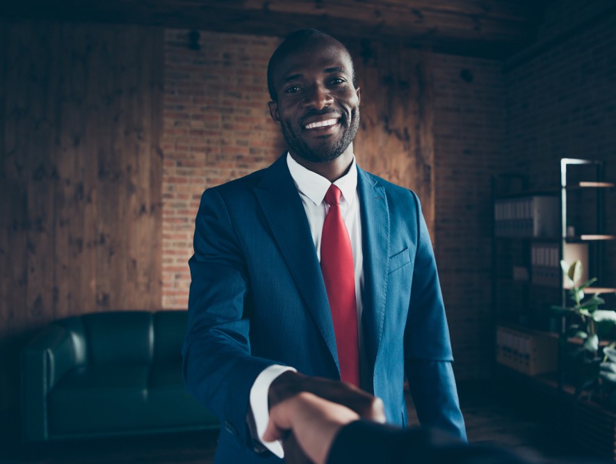 A man smiling and shaking hands with another person not included in picture.