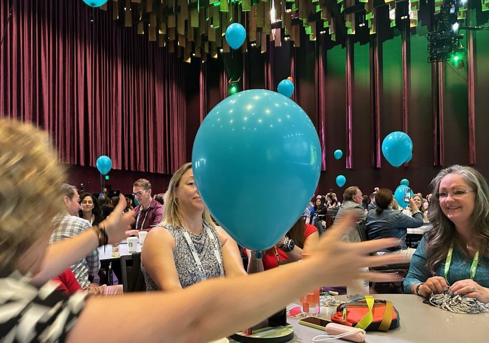 Photo of attendees at CEMA Summit 2024 interacting with balloons during a session.