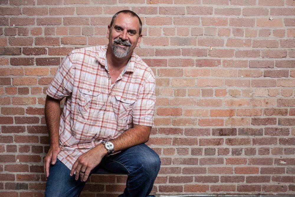 Photo of Mike McCallen standing in front of a brick wall.