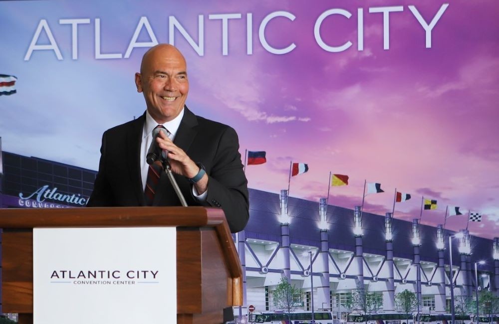 Photo of Larry Sieg, standing at a podium with a backdrop of the Atlantic City Convention Center in the background.