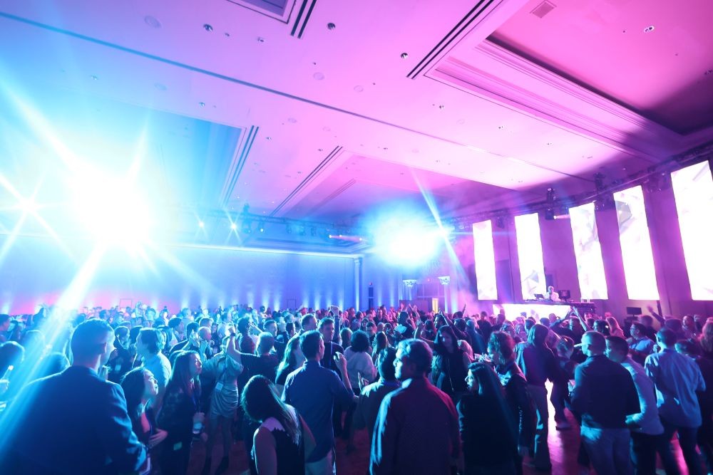 Photo of a crowd of attendees at a meeting, with spotlights in the room.