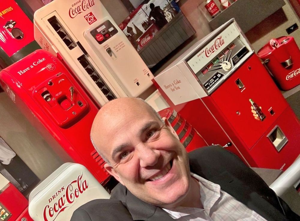 image of futurist Scott Steinberg standing in front of antique Coca-Cola vending machines.