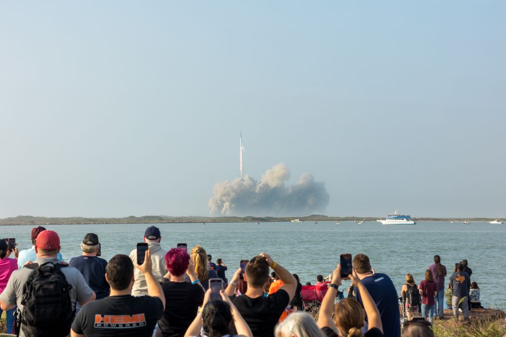 Photo of a crowd watching the lift-off of a SpaceX rocket in South Padre Island.