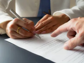 Image of two hands signing a legal contract.