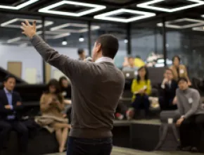 Photo of a man raising his hand while presenting at a meeting.